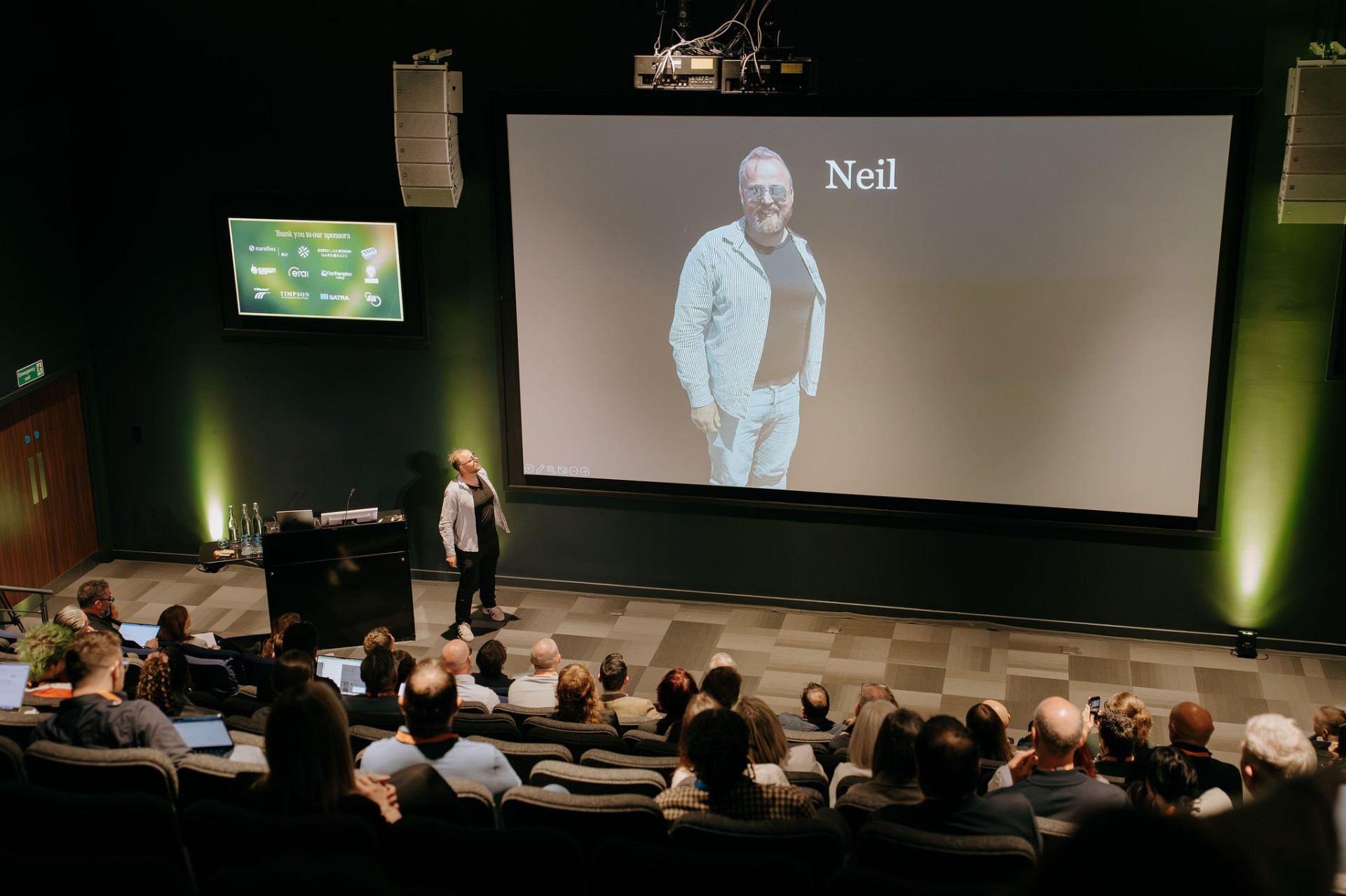 Speaker Neil on stage with audience portrait projection