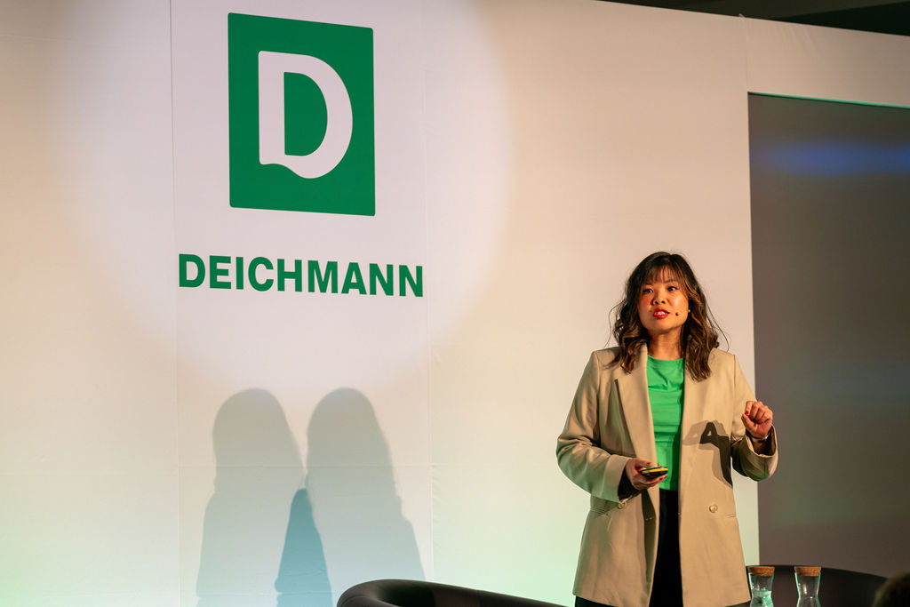Guest speaker presenting in front of Deichmann brand wall